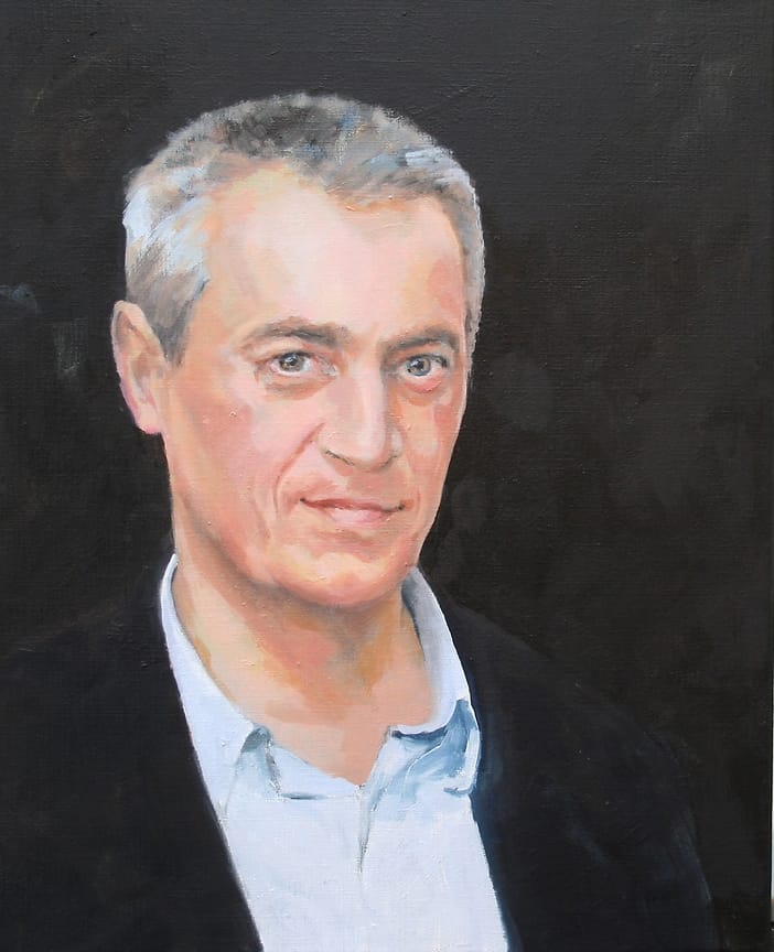 Friendly smiling middle age man, in a dark jacket and lightblue shirt.